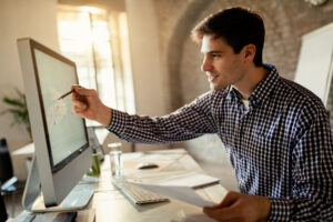 smiling businessman brainstorming while analyzing graph computer office